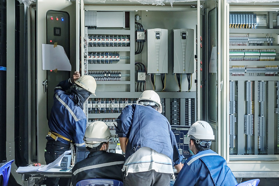 four operators carry out maintenance work on a control cabinet